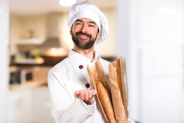 Biraz ekmek tutarak ve mutfakta bir şey tutan genç baker