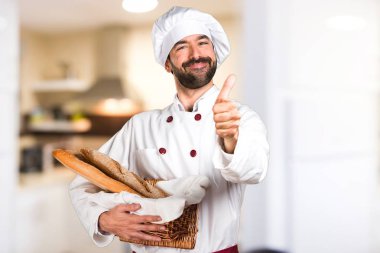 Biraz ekmek tutan genç baker ve mutfakta başparmak ile