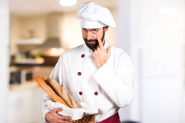 Biraz ekmek tutan ve bir şey mutfakta gösterilen genç baker