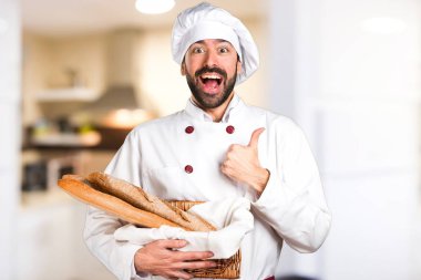 Biraz ekmek tutan genç baker ve mutfakta başparmak ile