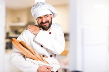 Genç baker ekmek omuz ağrısı ile mutfakta holding