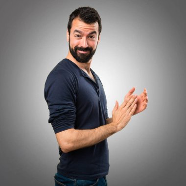 Sakal gri arka plan üzerinde alkış ile yakışıklı adam