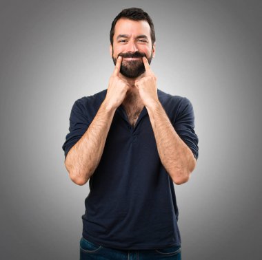 Gri arka plan üzerinde sakallı mutlu yakışıklı adam