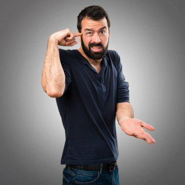 Gri arka plan üzerinde deli jest yapma sakallı yakışıklı adam