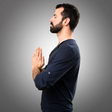 Gri arka plan üzerinde zen pozisyonda sakallı yakışıklı adam