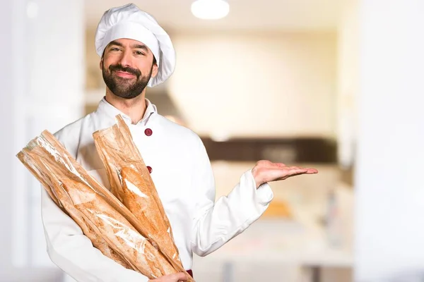 Jonge baker houden wat brood en houden van iets in de keuken — Stockfoto