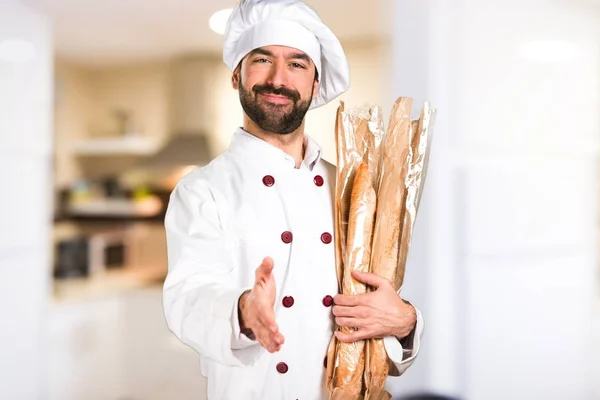 Młody piekarz trzyma chleb i dokonywanie transakcji w kuchni — Zdjęcie stockowe