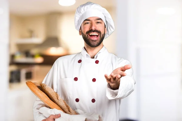 Junger Bäcker hält etwas Brot in der Küche und präsentiert etwas — Stockfoto