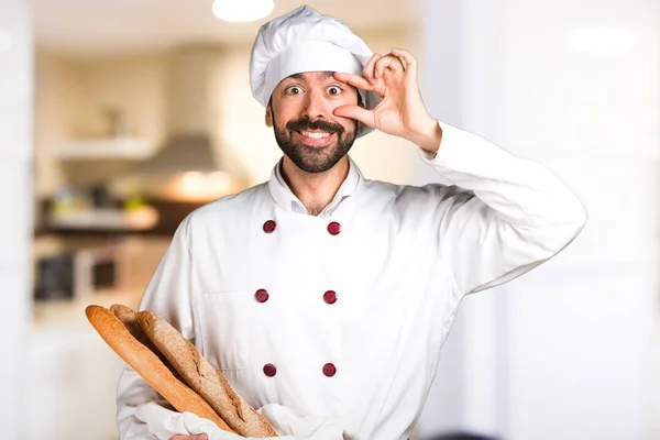 Jeune boulanger tenant du pain et montrant quelque chose dans la cuisine — Photo
