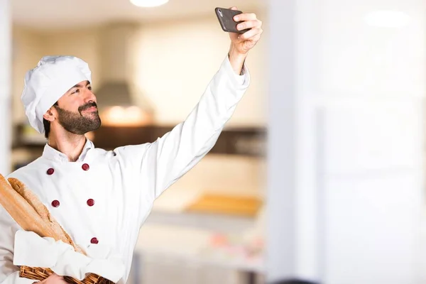 若いベイカー ・いくつかのパンを押しながら台所で、selfie を作る — ストック写真