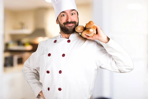 Młody piekarz trzyma chleb w kuchni — Zdjęcie stockowe