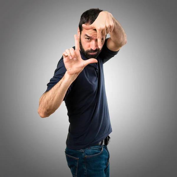 Przystojny mężczyzna z broda koncentrując się z jego palce na szarym tle — Zdjęcie stockowe