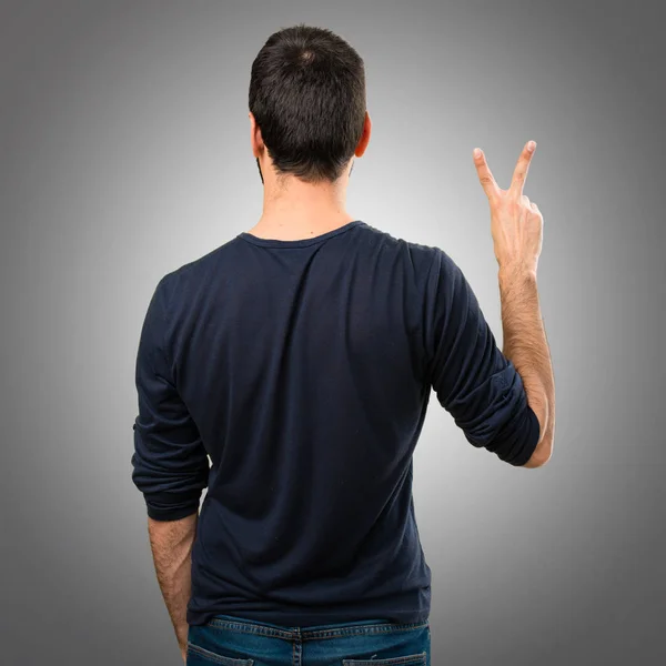 Hombre guapo con barba contando dos sobre fondo gris —  Fotos de Stock