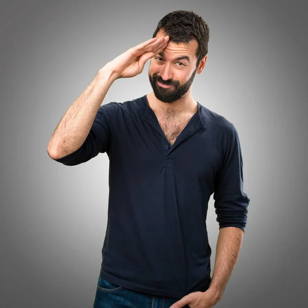 Bello uomo con barba che saluta su sfondo grigio — Foto Stock