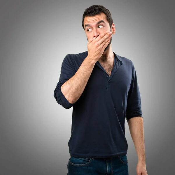 Pohledný muž s plnovousem, pokrývající ústa na šedém pozadí — Stock fotografie