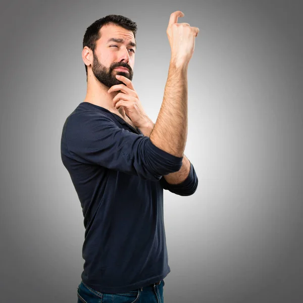 Knappe man met baard maken kleine grijze achtergrond aanmelden — Stockfoto