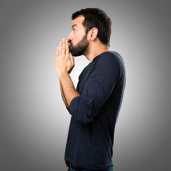 Handsome man with beard pleading on grey background — Stock Photo, Image