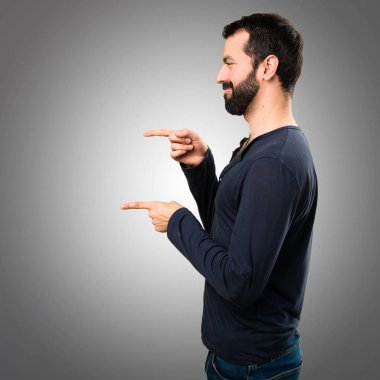 Lateral üzerinde gri backgrou işaret eden sakallı yakışıklı adam