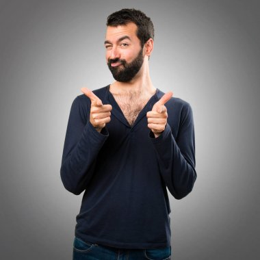 Gri arka plan üzerine açık işaret eden sakallı yakışıklı adam