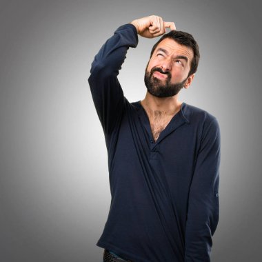 Gri arka plan üzerine şüpheleri sakallı yakışıklı adam