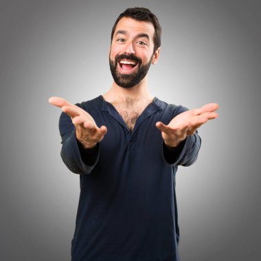 Bir şey gri arka plan üzerinde sunulması sakallı yakışıklı adam