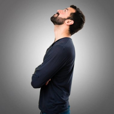 Gri arka plan üzerinde ararken sakallı yakışıklı adam