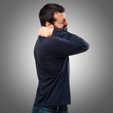 Gri arka plan üzerinde boyun ağrısı ile sakallı yakışıklı adam