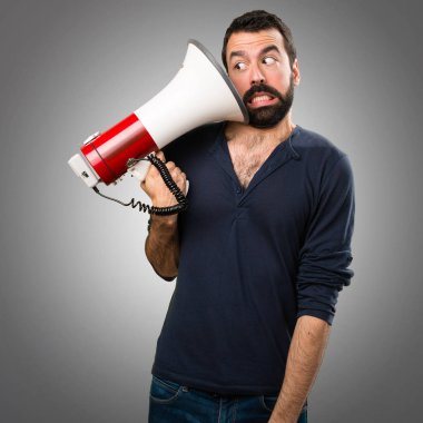 Bir megafon gri arka plan üzerinde tutarak sakallı yakışıklı adam