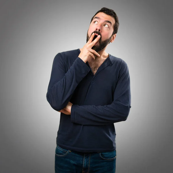 Pohledný muž s vousy dělat překvapení gesto na šedé poz — Stock fotografie