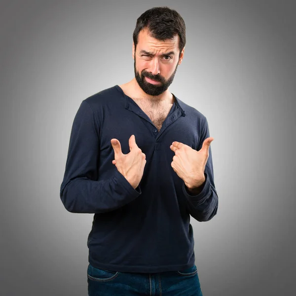 Hombre guapo con barba haciendo gesto sorpresa sobre fondo gris — Foto de Stock