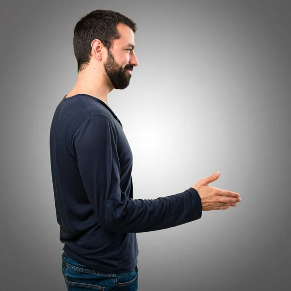 Bello uomo con la barba fare un accordo su sfondo grigio — Foto Stock