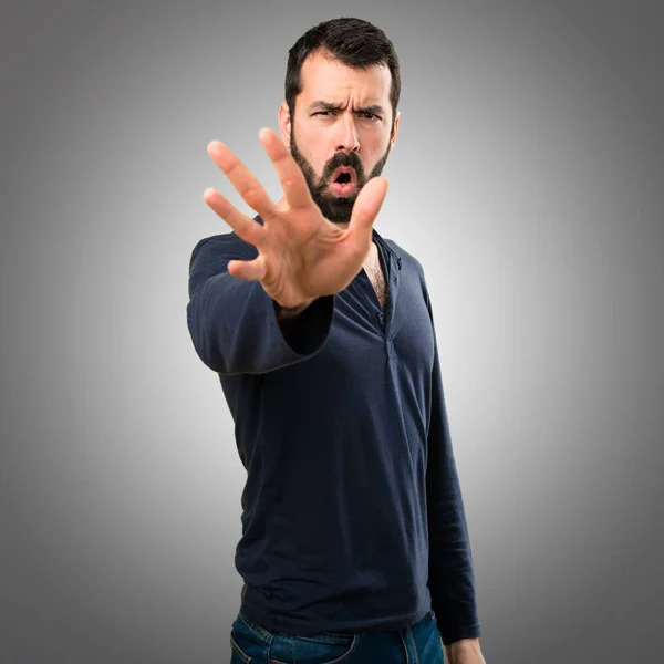 Bonito homem com barba fazendo sinal de parada no fundo cinza — Fotografia de Stock