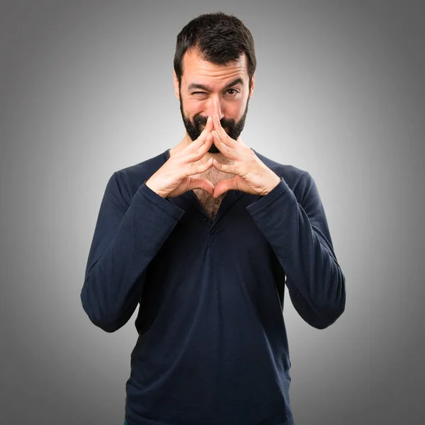 Hombre guapo con barba pensando en fondo gris —  Fotos de Stock