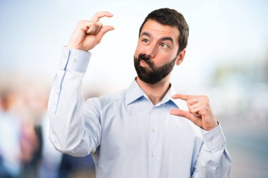 Küçük işareti odaklanmamış arka plan yapma sakallı yakışıklı adam