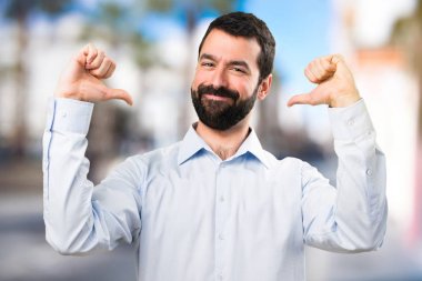 Sakallı odaklanmamış arka plan üzerinde kendisiyle gurur yakışıklı adam