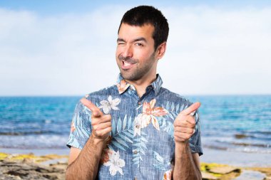 Açık Plajda işaret eden çiçek forması ile yakışıklı adam