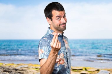 Plajda çiçek gömlek yapma para hareketi ile yakışıklı adam