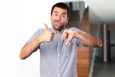 Yakışıklı adam evin içinde iyi-kötü işaret yapma