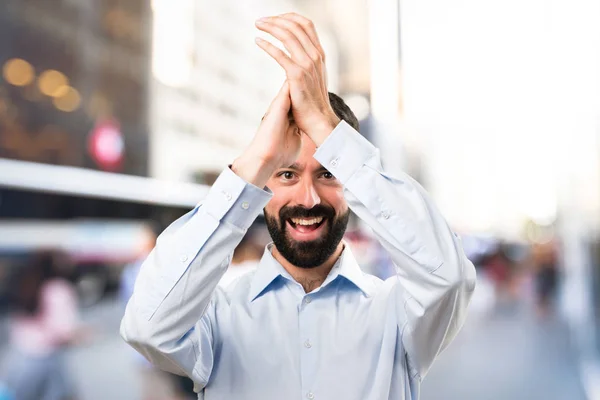 Bonito homem com barba aplaudindo em fundo desfocado — Fotografia de Stock