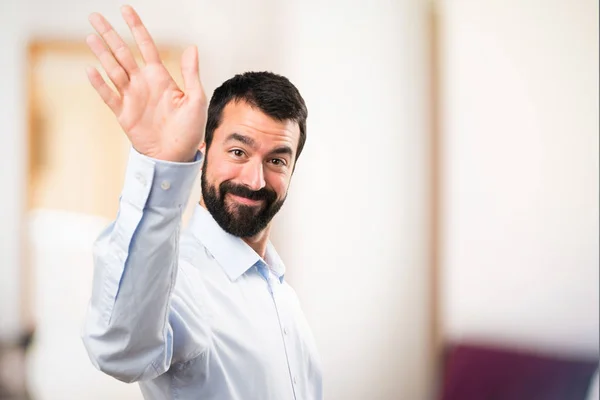 Handsome man with beard saluting on unfocused background — Stock Photo, Image