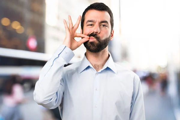 Schöner Mann mit Bart macht Schweigegegeste auf unkonzentriertem Rücken — Stockfoto