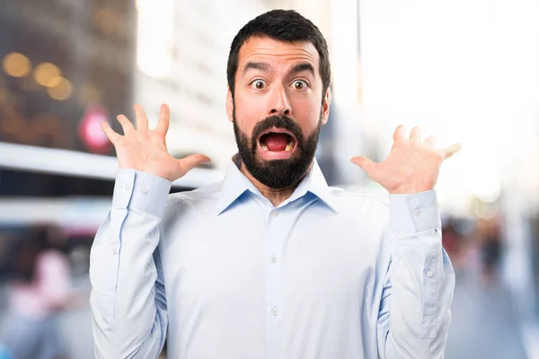 Pohledný muž s vousy dělat překvapení gesto na nezaostřený bac — Stock fotografie