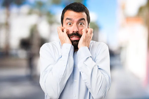 Asustado hombre guapo con barba sobre fondo desenfocado — Foto de Stock