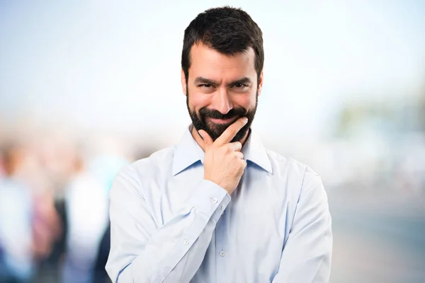 Schöner Mann mit Bart, der auf unkonzentriertem Hintergrund denkt — Stockfoto