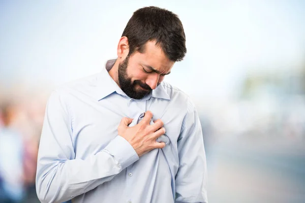 Hombre guapo con barba con dolor de corazón sobre fondo desenfocado —  Fotos de Stock