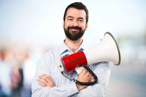 Bonito homem com barba segurando um megafone no backgro desfocado — Fotografia de Stock