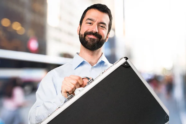 Gelukkig knappe man met baard die houden van een werkmap op ongericht b — Stockfoto
