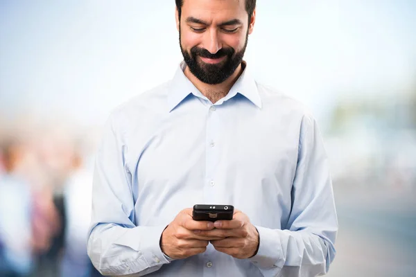 Szczęśliwy przystojny mężczyzna z brodą, mówienie do telefonów na nieostre bac — Zdjęcie stockowe