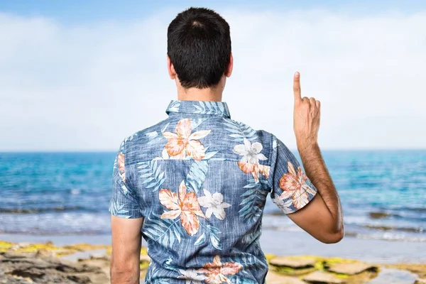 Hombre guapo con camisa de flores contando uno en la playa —  Fotos de Stock