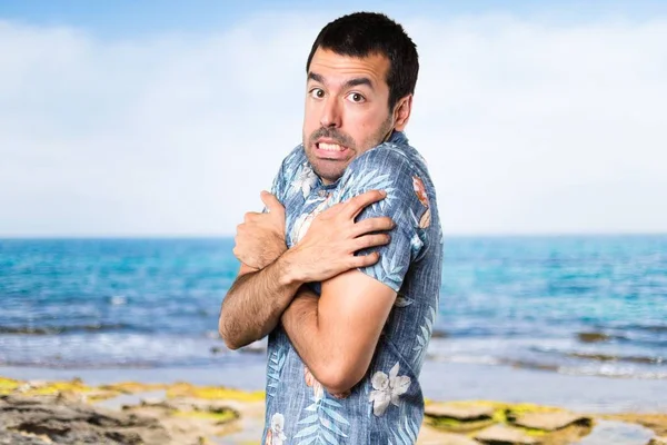 Hombre guapo con camisa de flores congelándose en la playa —  Fotos de Stock